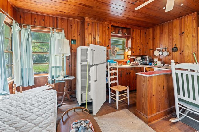 Kitchen featuring wooden ceiling, wooden walls, brown cabinetry, freestanding refrigerator, and a ceiling fan | Image 16