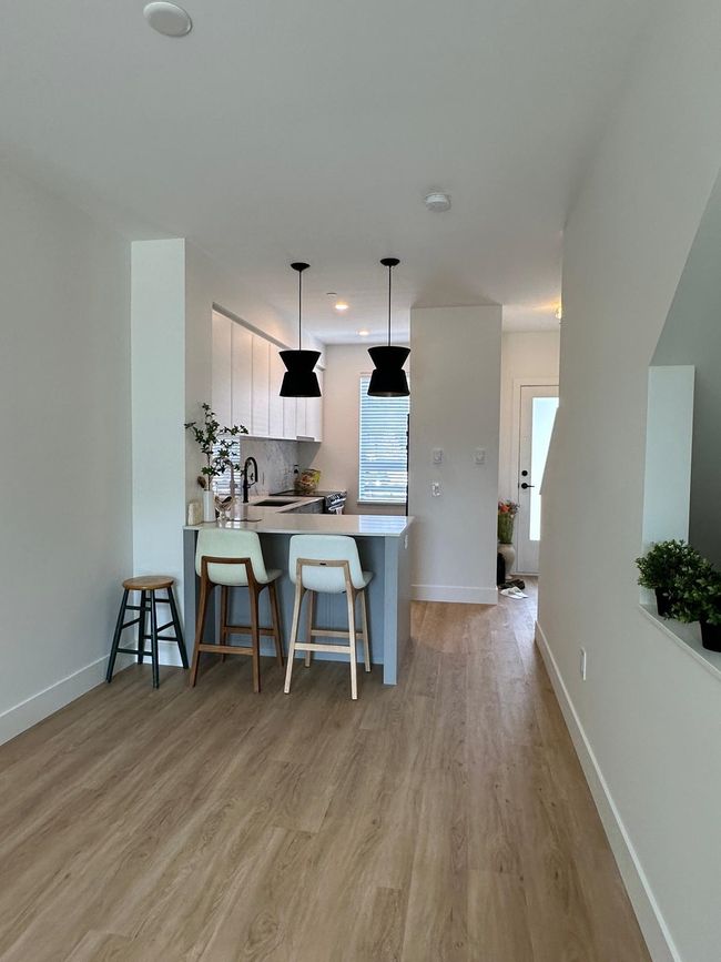Kitchen with a breakfast bar area, white cabinets, a peninsula, and light countertops | Image 5
