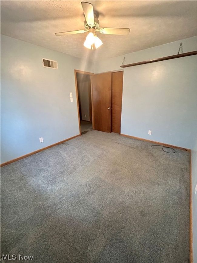 Unfurnished bedroom with light carpet, ceiling fan, and a closet | Image 15