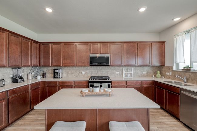Kitchen with light countertops, light wood-style flooring, stainless steel appliances, tasteful backsplash, and a sink | Image 14