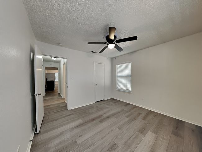 Unfurnished bedroom with attic access, wood finished floors, a textured ceiling, and baseboards | Image 13