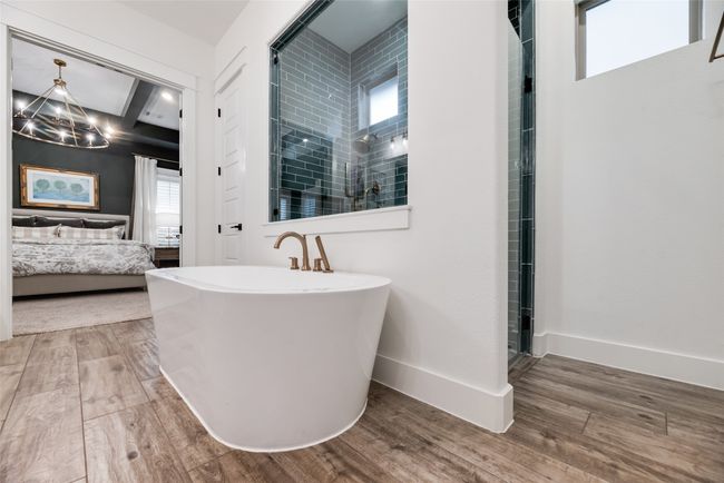Full bathroom featuring ensuite bathroom, a chandelier, wood finished floors, a stall shower, and a freestanding bath | Image 26