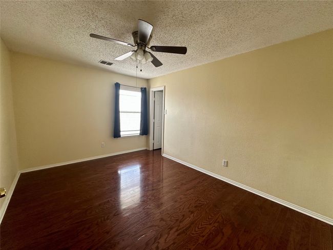 Empty room with a textured ceiling, dark wood finished floors, and ceiling fan | Image 20