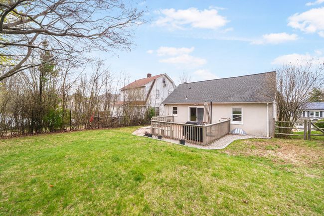 Rear view of house featuring fence, a shingled roof, stucco siding, a wooden deck, and a lawn | Image 32
