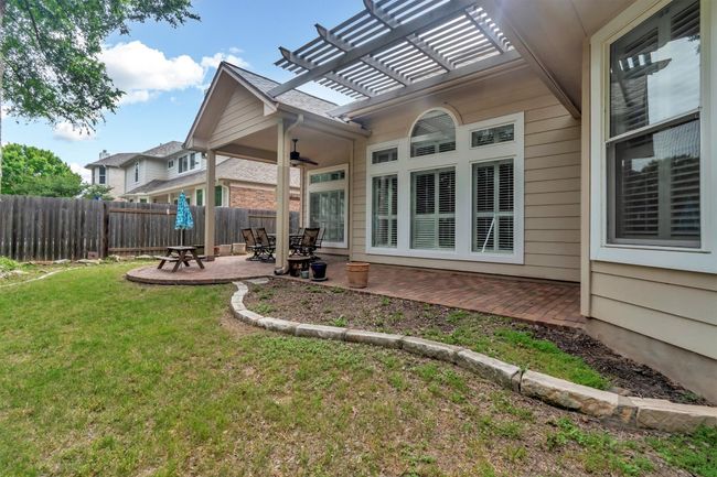 Rear view of house with a ceiling fan, fence, a pergola, a yard, and a patio area | Image 33