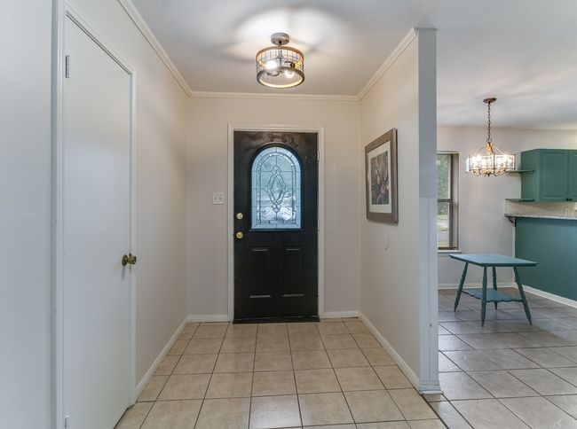 Foyer entrance with healthy amount of natural light, light tile patterned floors, a chandelier, and ornamental molding | Image 4