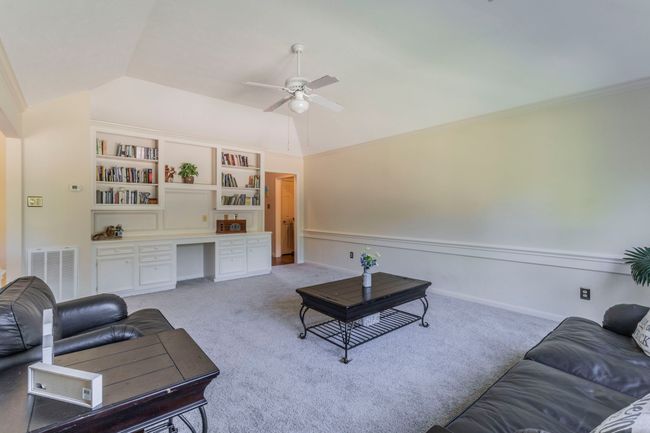 Living area with vaulted ceiling, ceiling fan, light colored carpet, a wainscoted wall, and ornamental molding | Image 18
