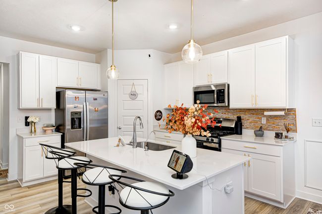 kitchen featuring white cabinetry, light wood-style flooring, a sink, stainless steel appliances, and backsplash | Image 10