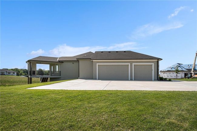 View of front of house with a garage, driveway, a front lawn, and roof with shingles | Image 65