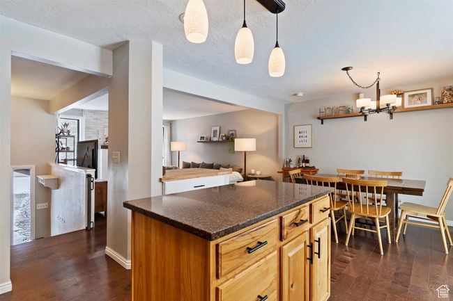 Kitchen featuring dark wood finished floors, a kitchen island, decorative light fixtures, and a chandelier | Image 8