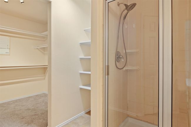 The primary bathroom also features a separate walk in shower and built in shelves for extra storage for linens and towels. | Image 16