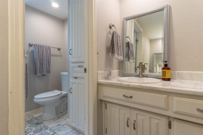 Bathroom featuring vanity, marble look tiles, and toilet | Image 23