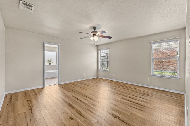 Spare room with a textured ceiling, a ceiling fan, healthy amount of natural light, and light wood-type flooring | Image 8