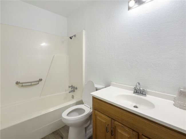 Bathroom with vanity, washtub / shower combination, and a textured wall | Image 15