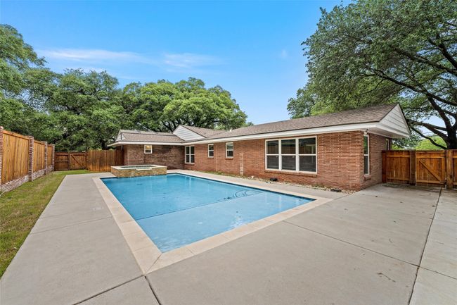 View of pool featuring a gate, a patio area, a fenced backyard, and a pool with connected hot tub | Image 38