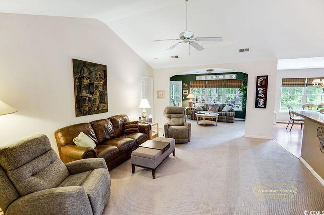 Living area featuring a ceiling fan, vaulted ceiling, arched walkways, and light carpet | Image 7