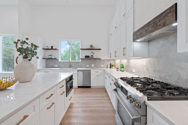Kitchen with custom wall range hood, stainless steel appliances, open shelves, and white shaker style cabinetry | Image 14