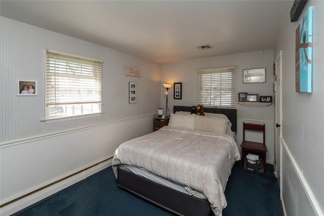 Bedroom with a baseboard heating unit, visible vents, and carpet | Image 14