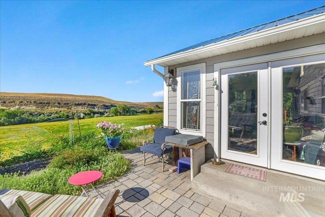 Patio, with French doors into sunroom and view of pastures and the river. | Image 30