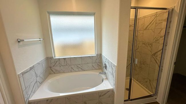 Bathroom featuring a stall shower, a bath, and a textured wall | Image 25