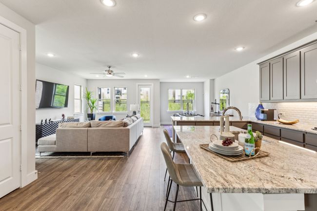 Kitchen with recessed lighting, a kitchen breakfast bar, gray cabinets, light stone countertops, and wood finished floors | Image 34