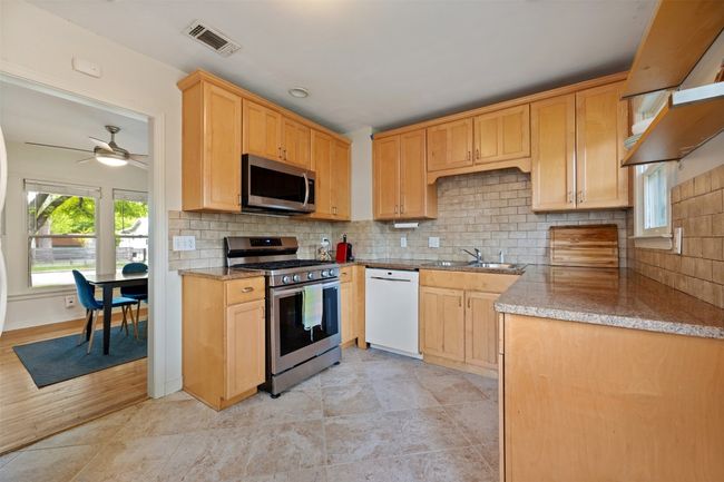 Large kitchen with recent cabinets, stone counters, tile backsplash, and open shelving | Image 6