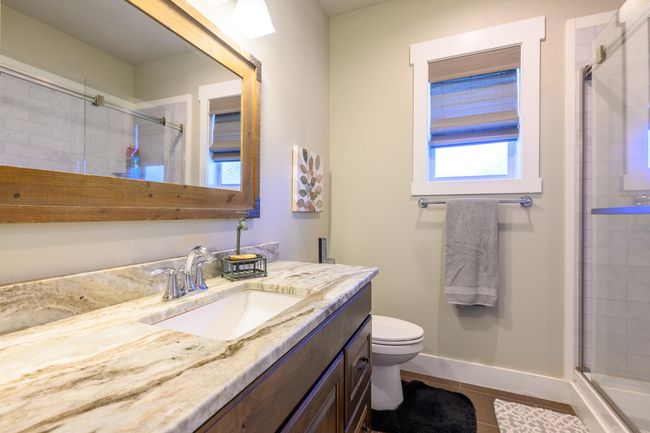 Full bath featuring vanity, toilet, a tile shower, and tile patterned flooring | Image 24