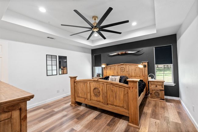 Bedroom featuring hardwood / wood-style flooring, ceiling fan, and a tray ceiling | Image 12