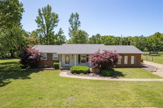 Ranch-style home with a porch, brick siding, a front yard, and roof with shingles | Image 27