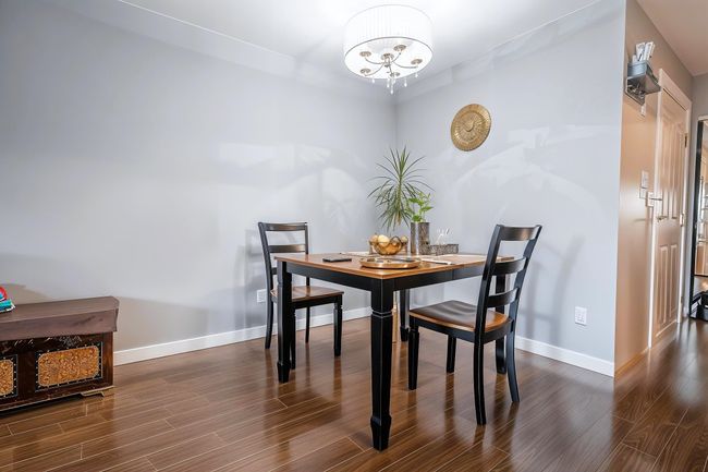 Dining area featuring wood finished floors, a notable chandelier, and baseboards | Image 11