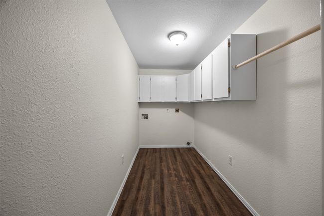 Laundry area featuring cabinet space, baseboards, washer hookup, dark wood-style floors, and a textured wall | Image 13
