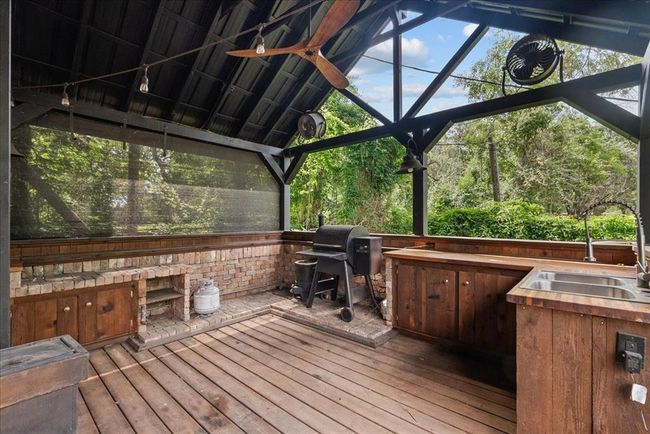 Fully equipped outdoor kitchen with smoker, brick accents, and built-in sink under a charming pitched roof. | Image 38
