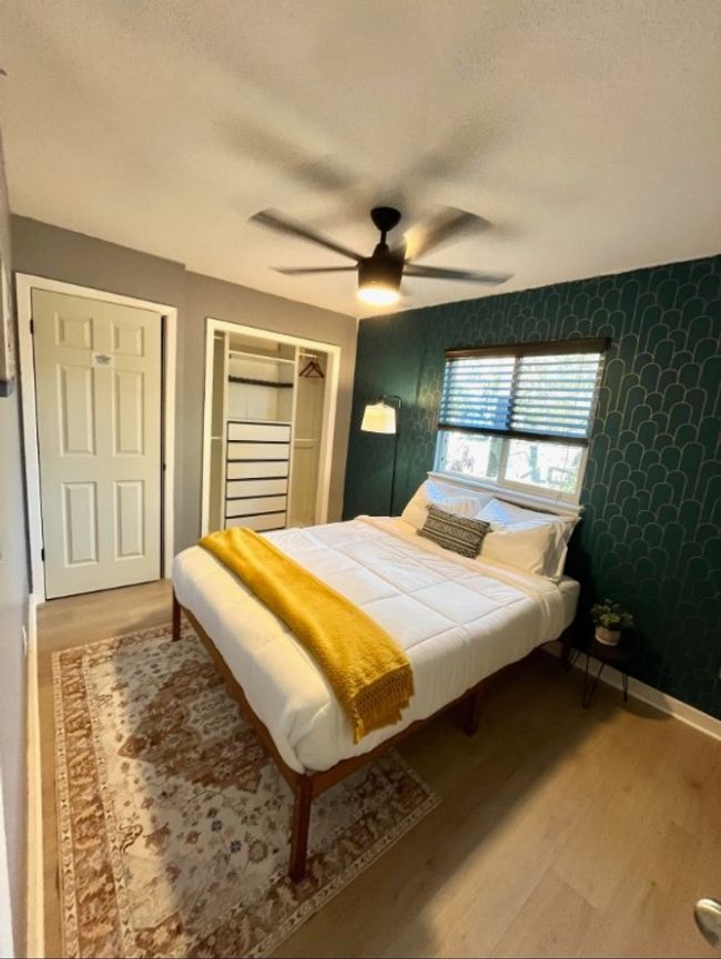 Bedroom featuring wood finished floors, wallpapered walls, ceiling fan, a textured ceiling, and a closet | Image 6