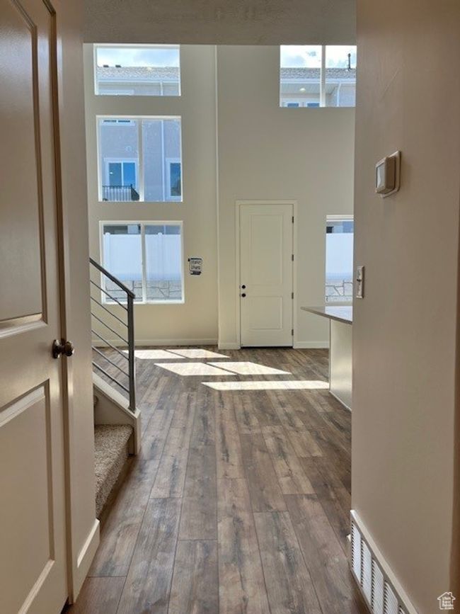 Entryway featuring visible vents, baseboards, a towering ceiling, hardwood / wood-style flooring, and stairs | Image 5