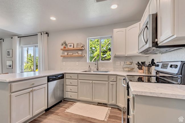 Kitchen featuring stainless steel appliances, a peninsula, healthy amount of natural light, light countertops, and recessed lighting | Image 9