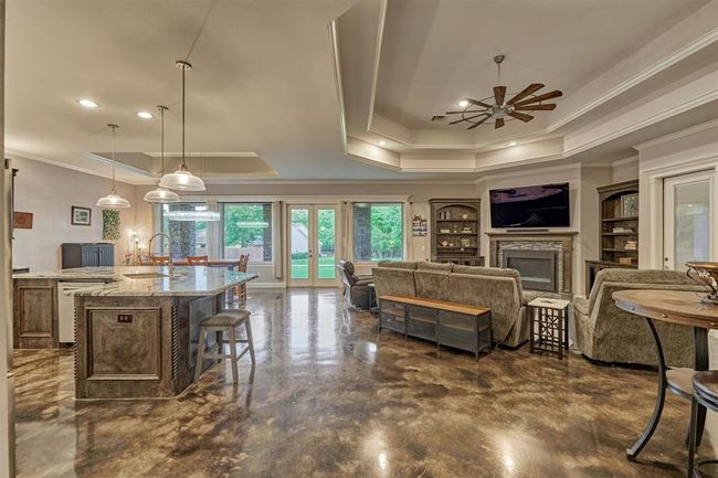 This expansive open-concept living space seamlessly combines the living room, kitchen, and dining area. A large center island anchors the kitchen, providing ample prep space and casual seating. | Image 17