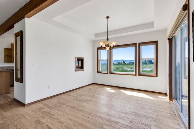 Unfurnished room with a tray ceiling, a chandelier, light wood-style floors, and baseboards | Image 19
