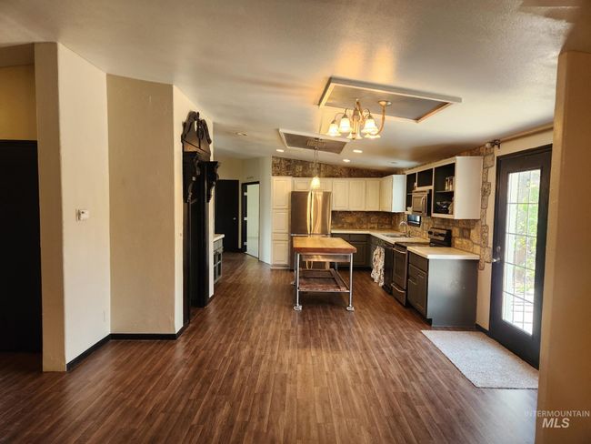 Kitchen featuring stainless steel appliances, dark wood-style floors, backsplash, and white cabinetry | Image 9
