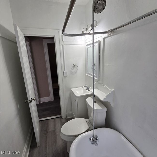 Bathroom with wood finished floors, toilet, vanity, baseboards, and a freestanding tub | Image 10