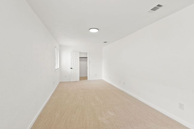 Bedroom 1 with light colored carpet, baseboards, and visible vents | Image 18