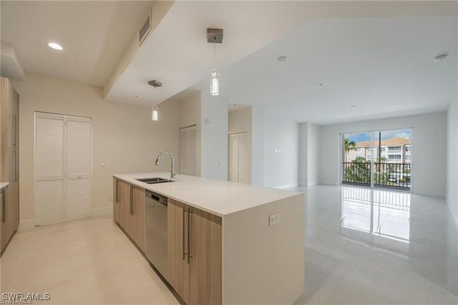 Kitchen featuring light countertops, a sink, open floor plan, dishwasher, and decorative light fixtures | Image 8