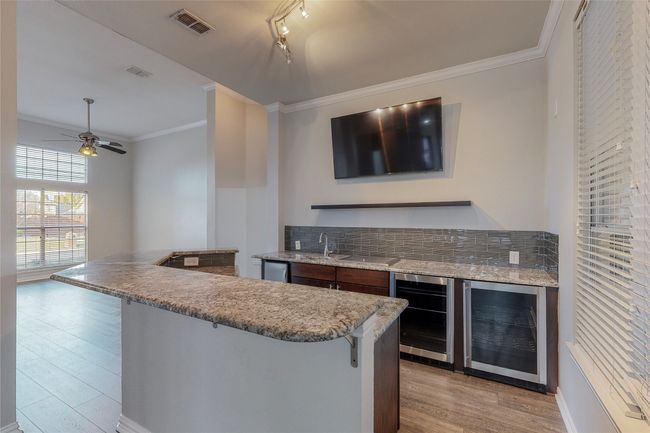 Kitchen with wine cooler, a breakfast bar area, light wood-style floors, backsplash, and ornamental molding | Image 8