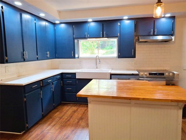 Kitchen featuring blue cabinetry, under cabinet range hood, a sink, dark wood-style flooring, and recessed lighting | Image 4