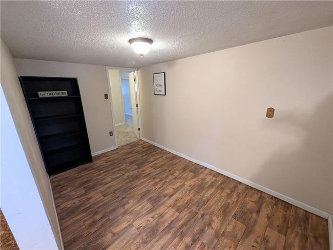 Empty room featuring wood finished floors, a textured ceiling, and baseboards | Image 17