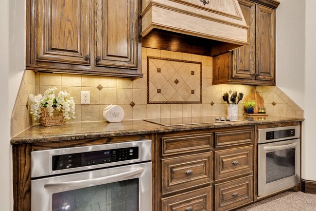 Kitchen featuring premium range hood, stainless steel oven, black electric stove top | Image 12