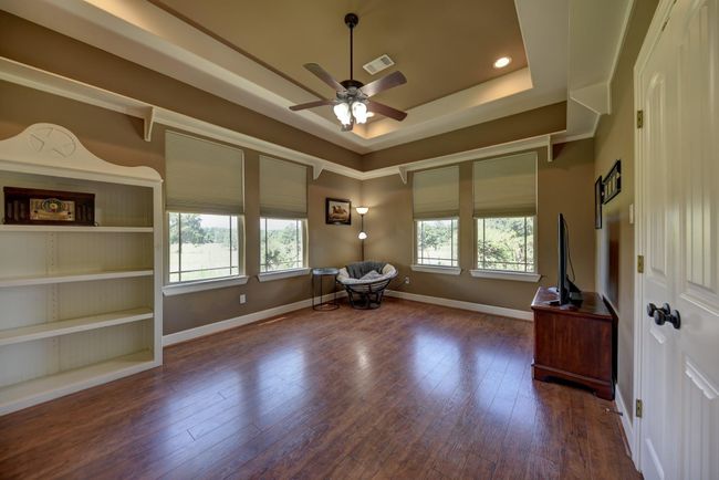 Flex room that can be a bedroom, media, gameroom or craft/hobby room with large windows offering natural light and a closet for storage. Features a ceiling fan, tray ceiling, and neutral tones for a cozy atmosphere. | Image 25