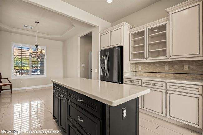Kitchen featuring visible vents, stainless steel refrigerator with ice dispenser, light countertops, dark cabinetry, and decorative backsplash | Image 17