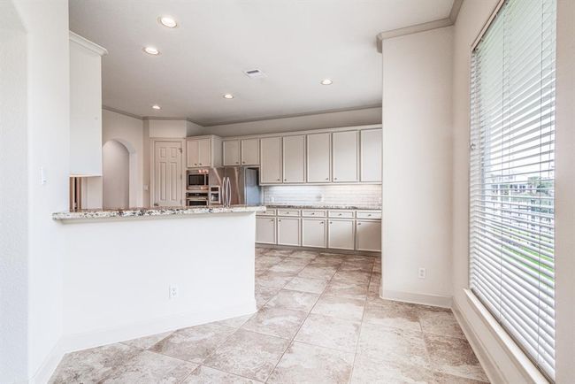 View of the beautiful marina from the breakfast bar area. Continuous tile flooring, recessed lighting, crown molding, high ceilings and neutral decor throughout this entire home. It's move in ready & Stunning! | Image 21
