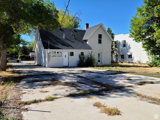 View of side of home featuring concrete driveway, a chimney, and roof with shingles | Image 4
