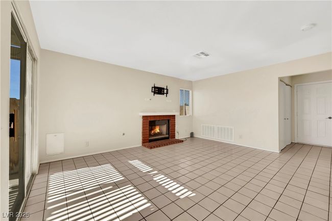 Unfurnished living room featuring light tile patterned floors, a brick fireplace, and visible vents | Image 16